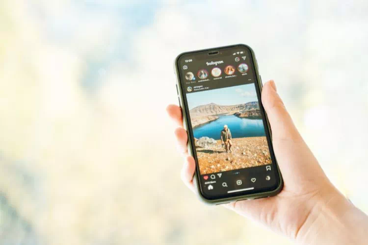 Personne tenant un smartphone avec une photo d'un feed Instagram