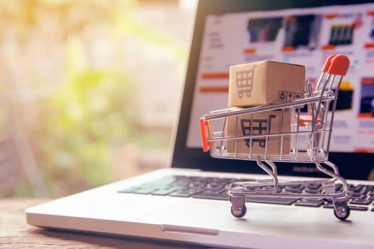 Concept d'achat en ligne avec un caddie miniature posé sur un ordinateur portable
