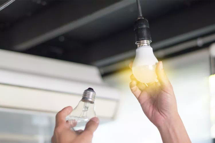 Homme changeant une ampoule à filament par une ampoule LED