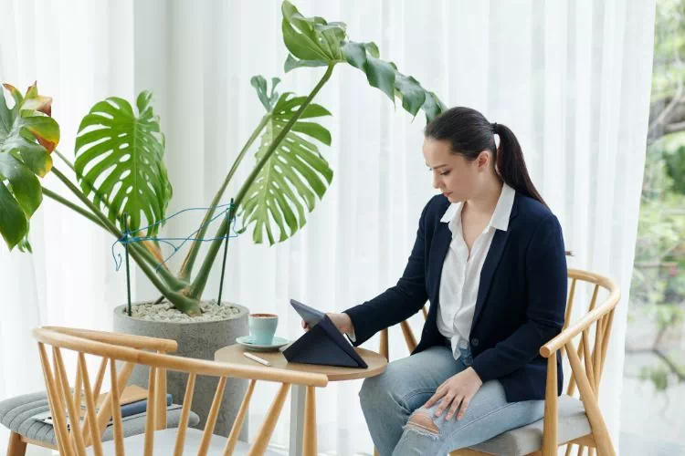 Femme assise, en train de lire un article sur sa tablette