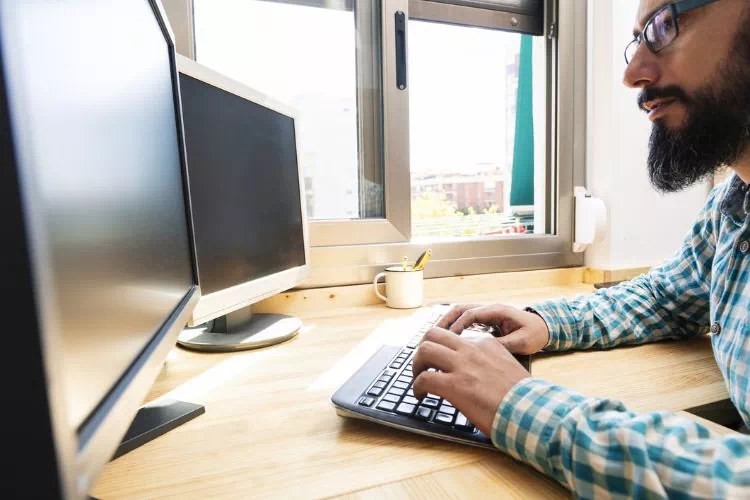 Homme travaillant sur un ordinateur avec un second écran éteint