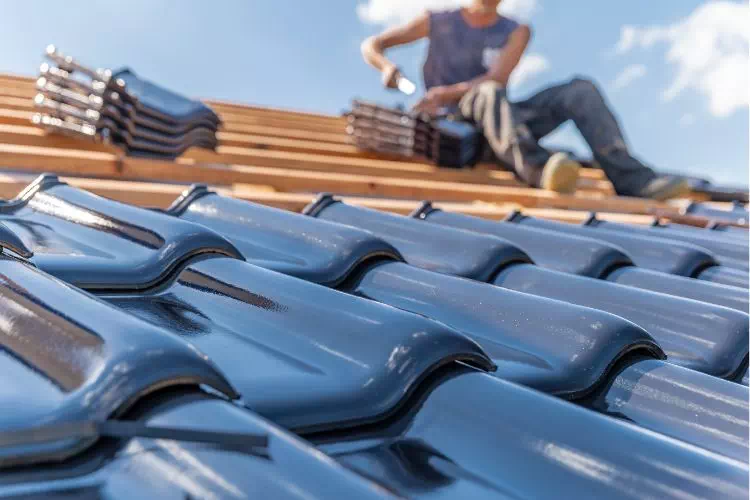 Couvreur sur un toit en train de poser des tuiles