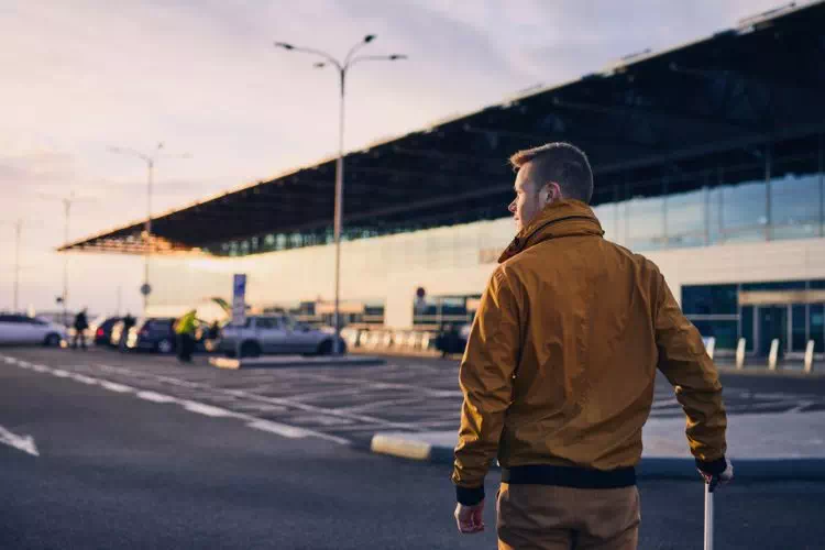 Homme avec sa valise sur le parking d'un aéroport