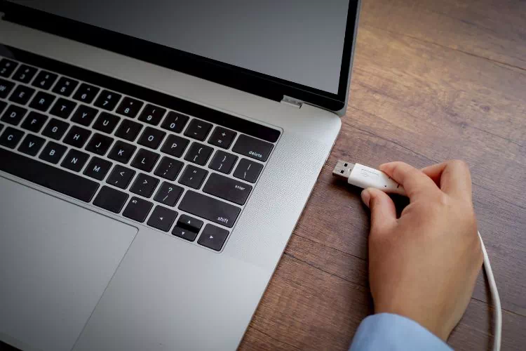 Homme connectant un cordon USB sur son Mac