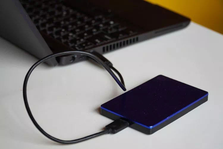 Disque dur externe avec liseré bleu branché à un ordinateur portable