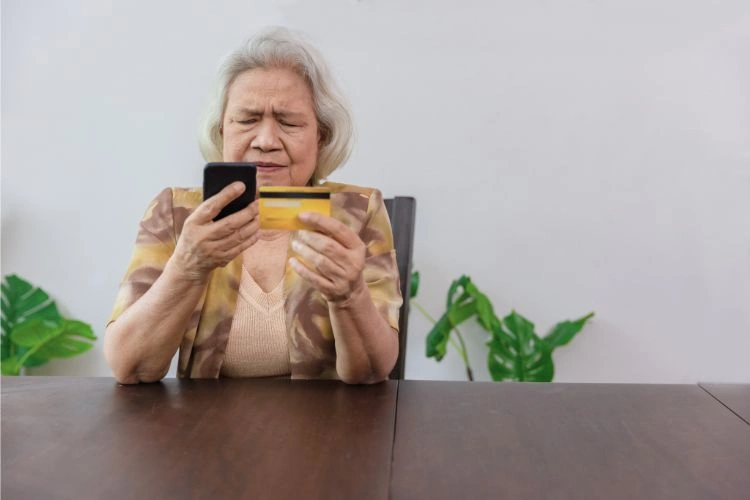 Femme avec sa carte bancaire et son téléphone confuse parce qu'elle vient de se faire piraté