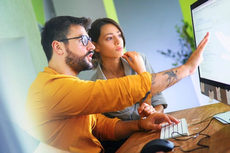 Homme formant une femme à l'utilisation d'un logiciel OCR
